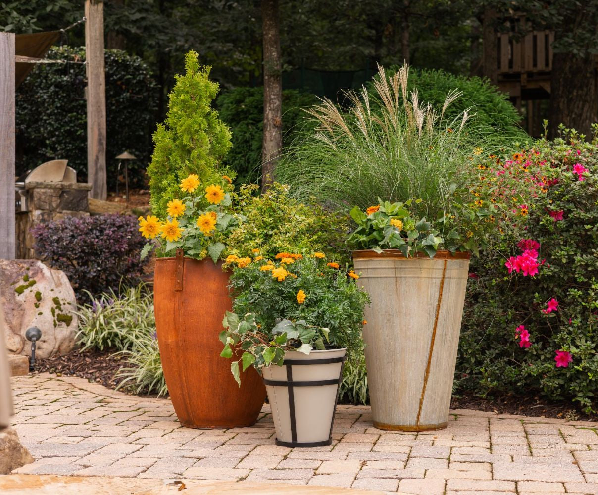 Decorative honey bee outdoor planters in a garden with potted plants and flowers on a stone patio