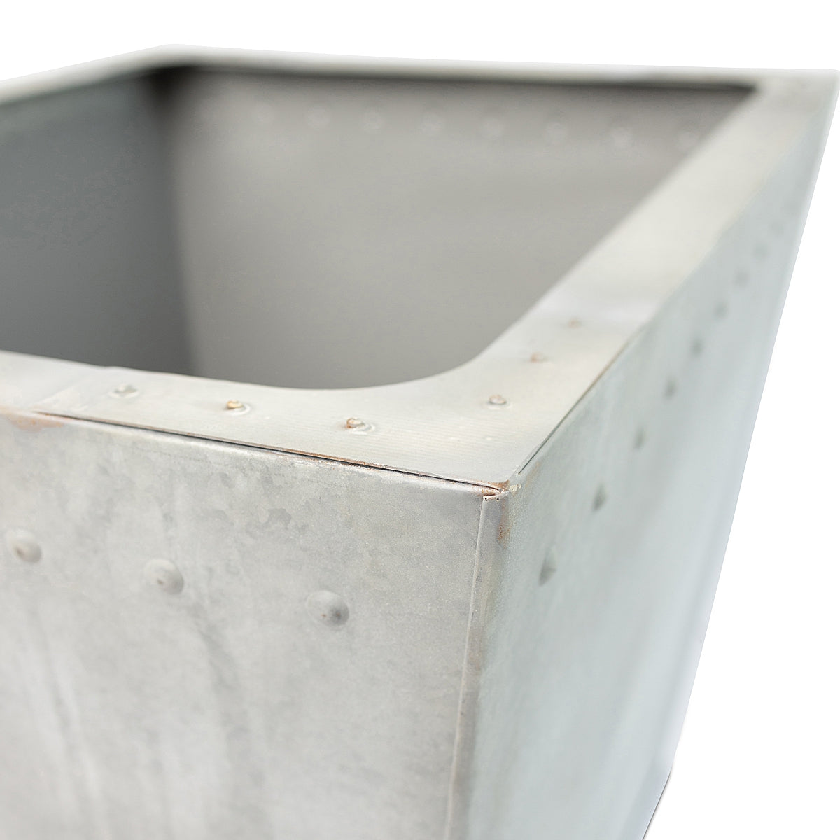 Close-up of corner of the Rustic Rectangle Water Trough Metal Planter with a rugged galvanized steel finish and visible rivet details, inspired by traditional farm troughs on a white background.