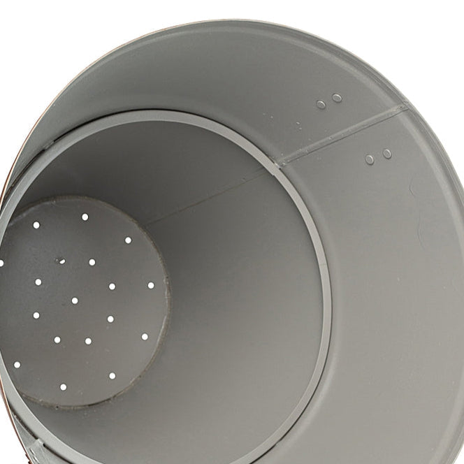 Close-up of the interior of large metal planter showcasing the drainage holes on a white background.