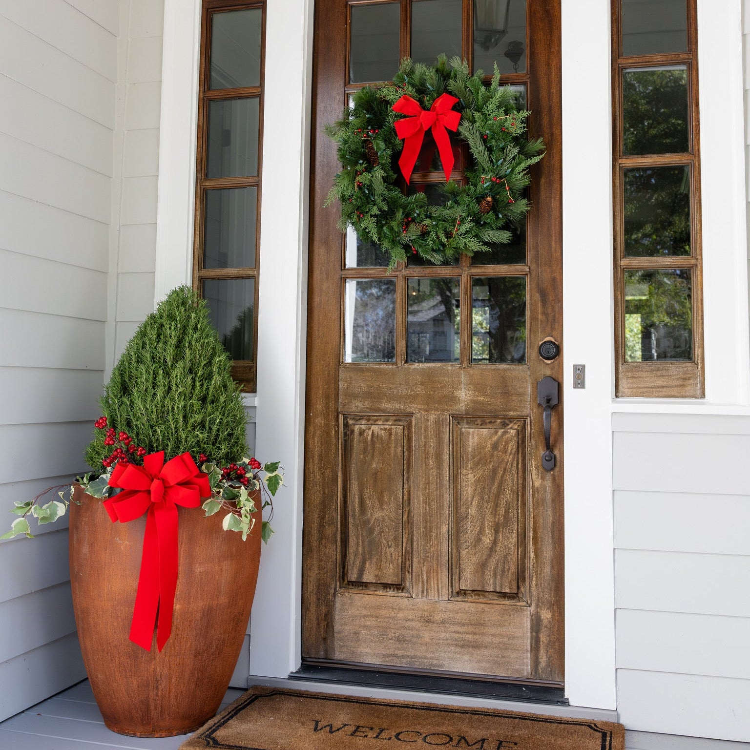 Wooden front door with wreath and potted plants on a porch