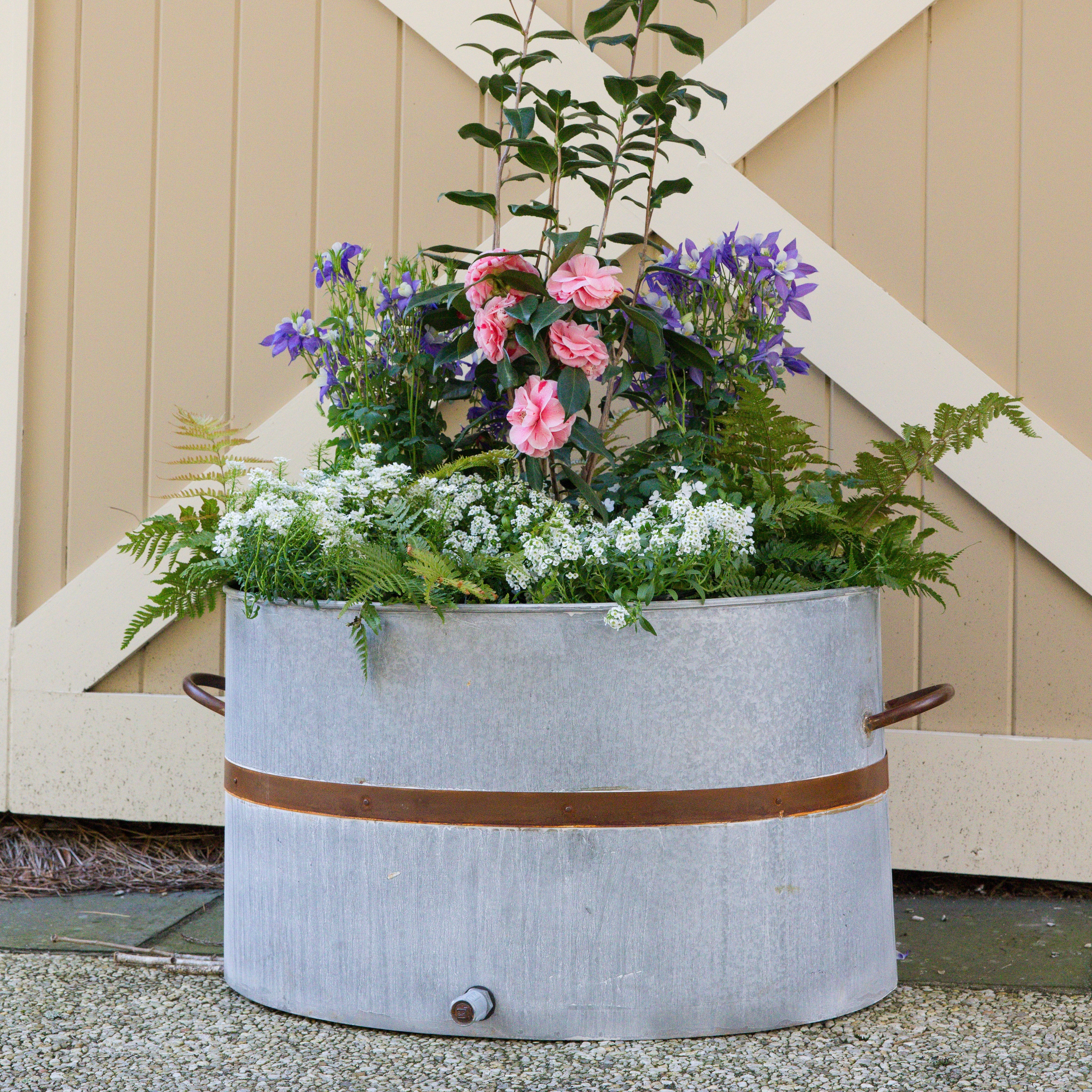 Decorative honey bee outdoor metal planter with flowers against a wooden background