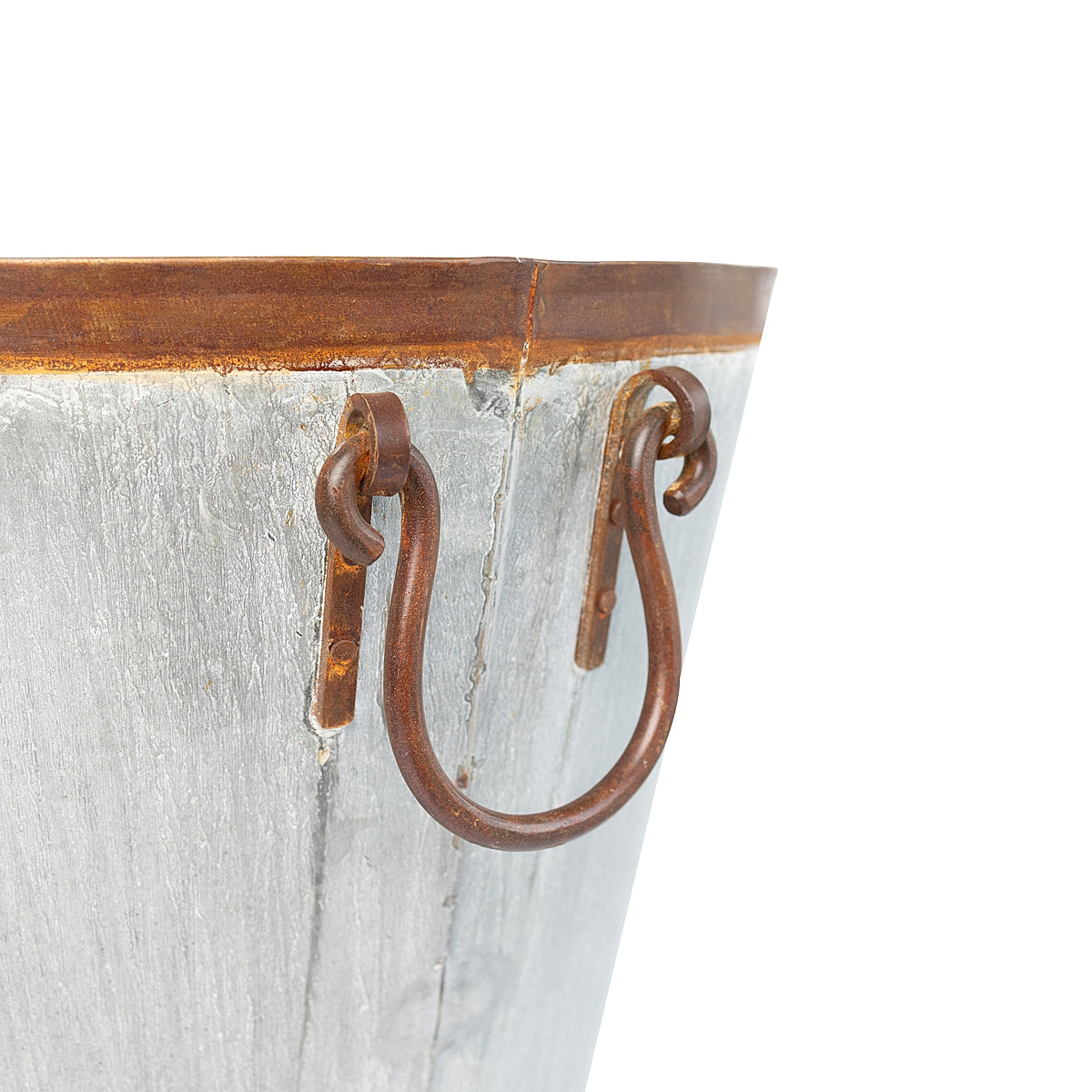 Close up of handle on a galvanized tapered steel planter with a distressed finish and sturdy ring handles, inspired by French grape harvesting baskets