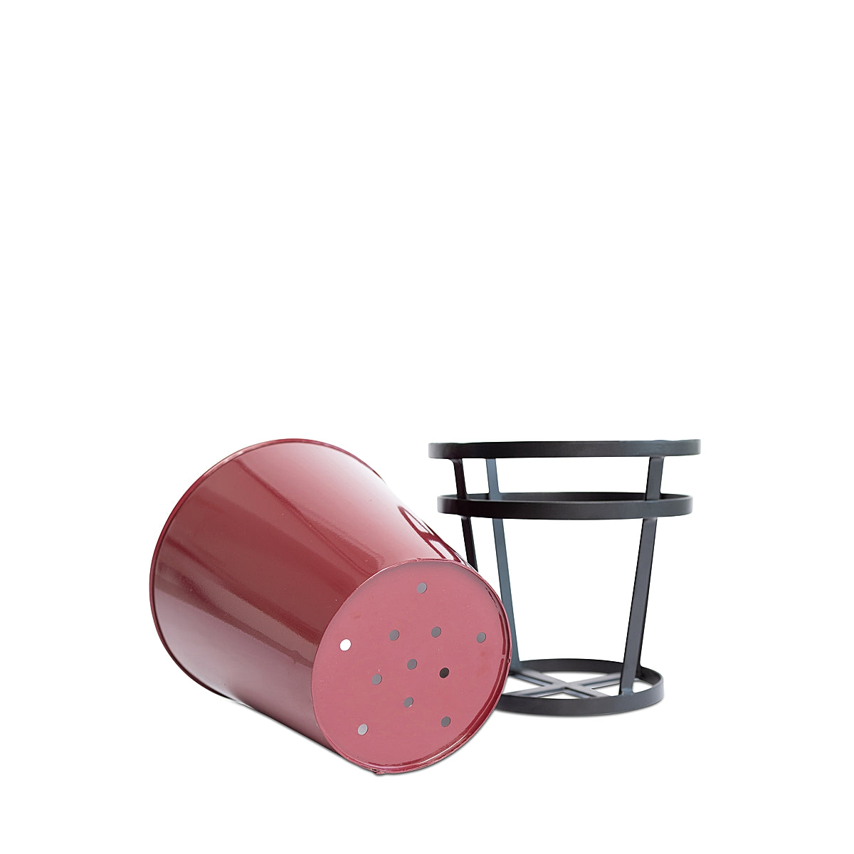 Red Modern Rustic Framed Steel Planter, tipped on its side to show the drainage holes on the bottom, with its black metal frame standing next to it on a white background