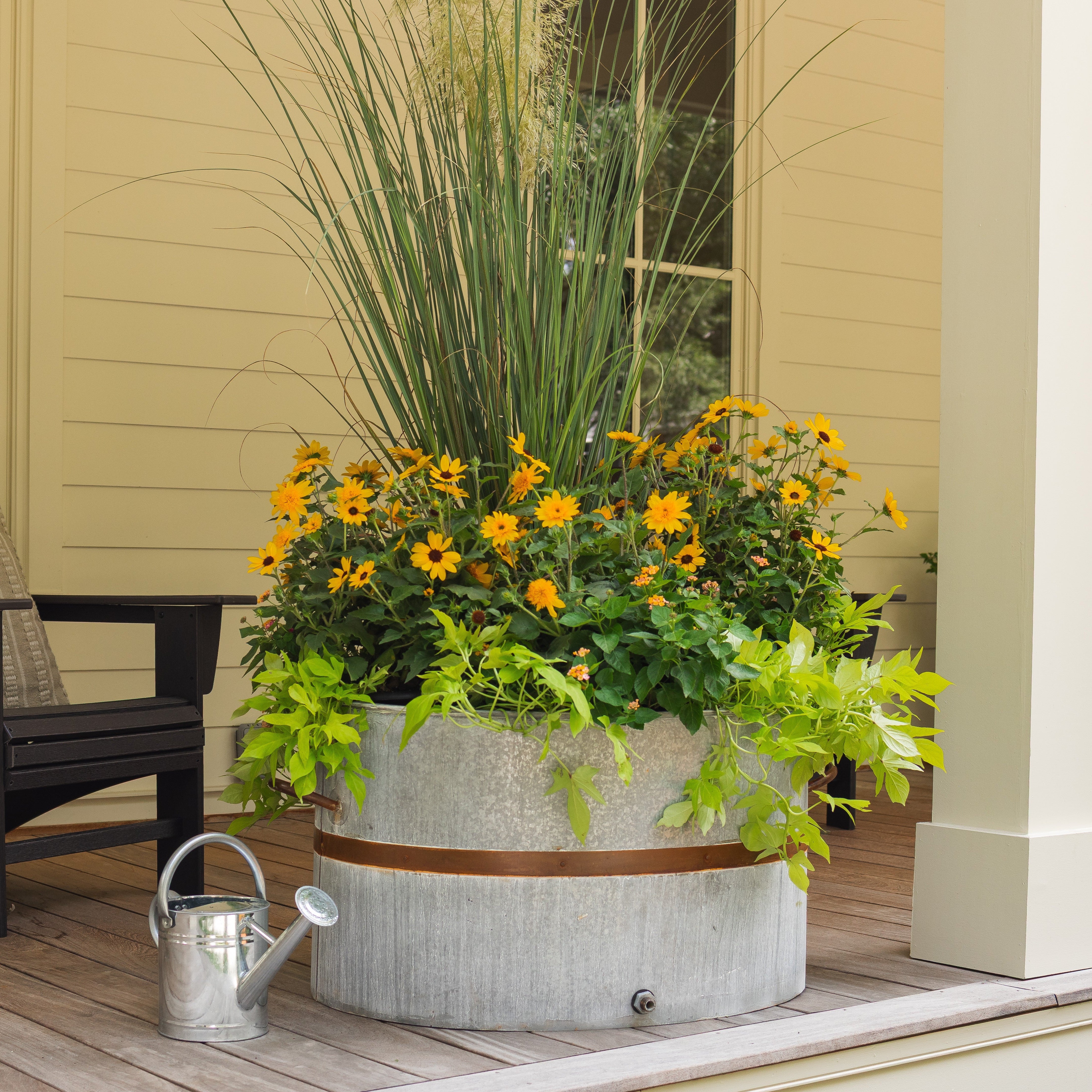 rustic oval water trough planter with flowers on a farmhouse front porch