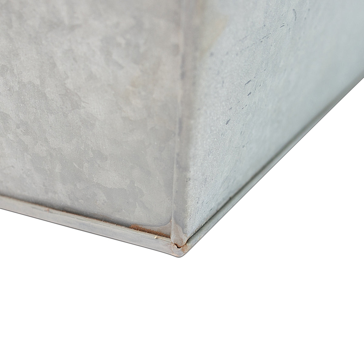 Close-up of bottom corner of the Rustic Rectangle Water Trough Metal Planter with a rugged galvanized steel finish and visible rivet details, inspired by traditional farm troughs on a white background.