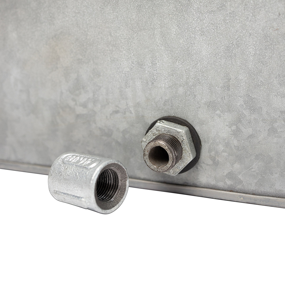 Close-up of drain plug details o the Rustic Rectangle Water Trough Metal Planter with a rugged galvanized steel finish and visible rivet details, inspired by traditional farm troughs on a white background.