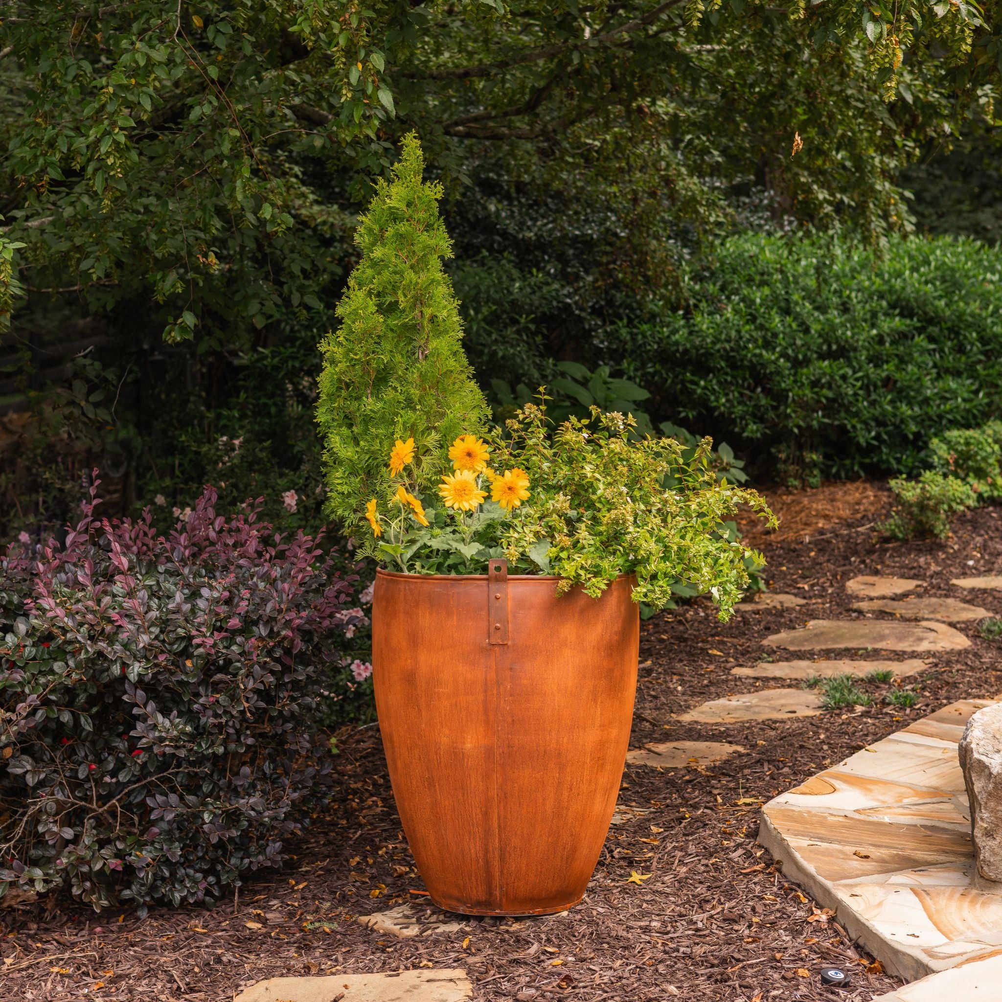Decorative vintage planter with greenery and flowers in a garden setting.