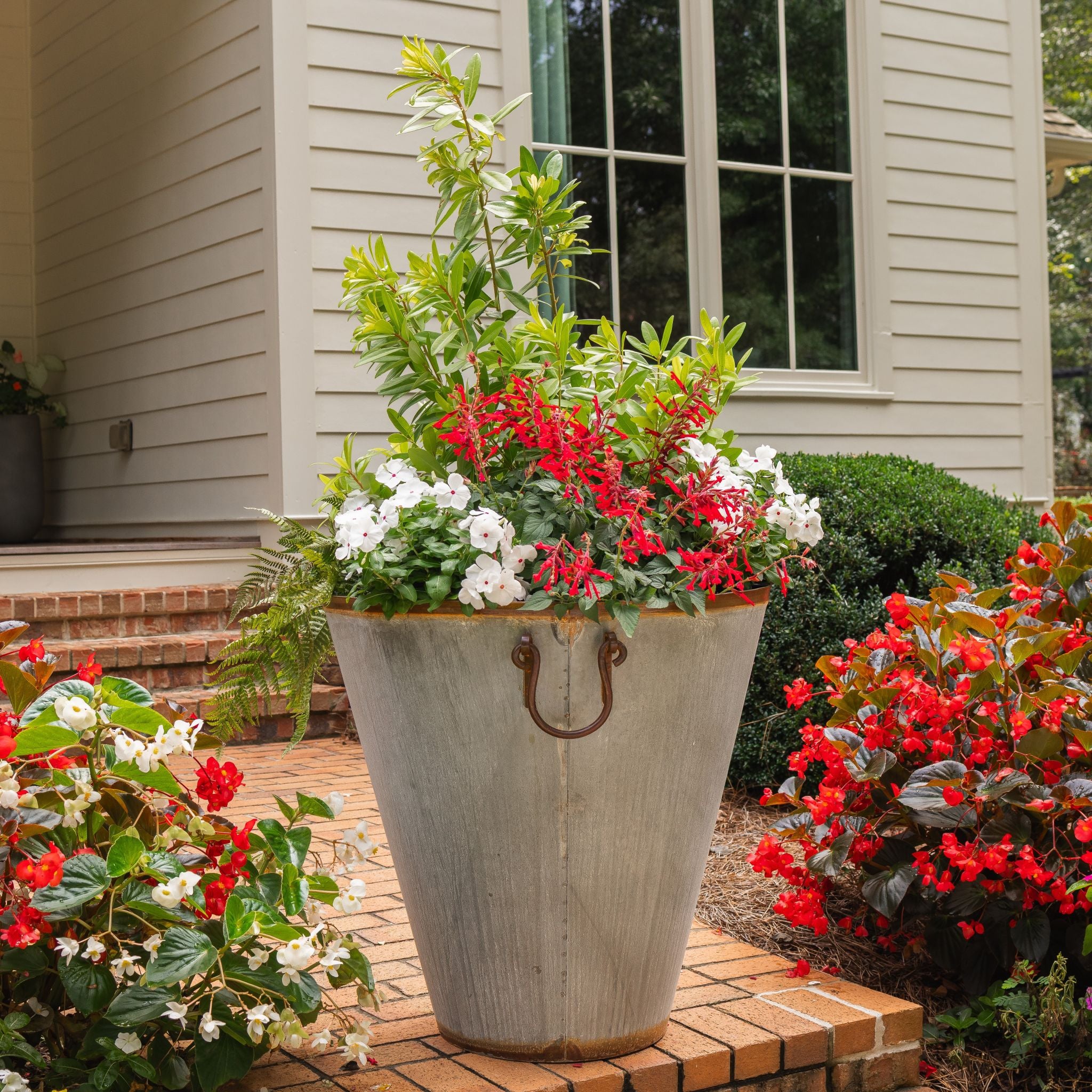Honey Bee Outdoor decorative large planter with flowers on a patio in front of a house.