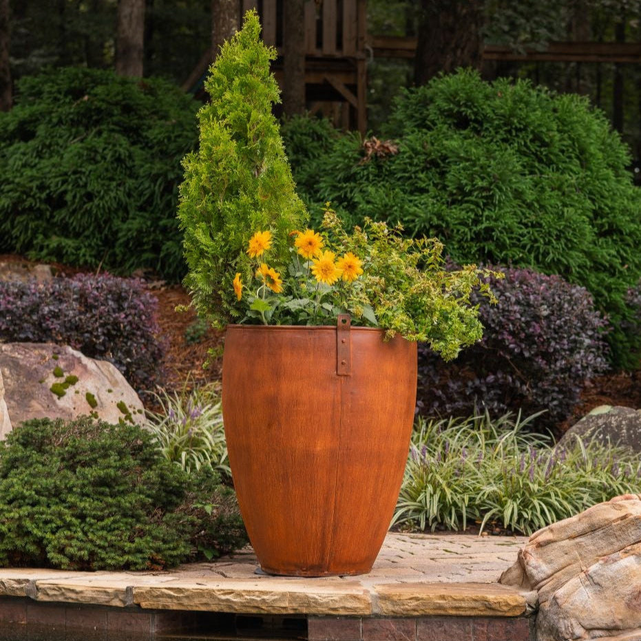 Large outdoor pot by a pool with garden and trees in the background